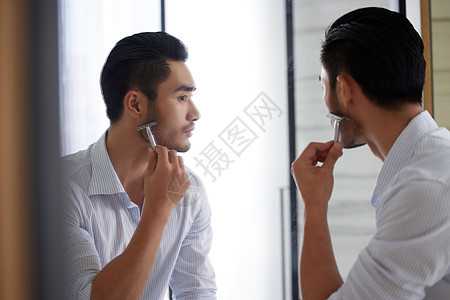 成熟男士对着镜子刮胡子背景图片