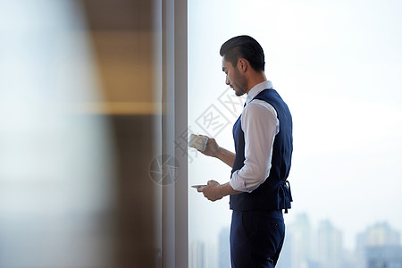 喝的成熟商务男性站在窗前喝咖啡背景
