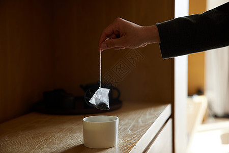 往茶杯里放茶包手部特写图片