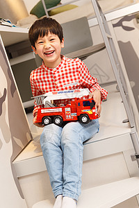 高兴小男孩在卧室里拿着玩具车图片