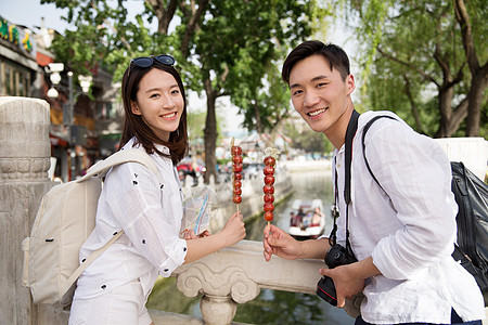 度假青年情侣旅游拿着糖葫芦图片