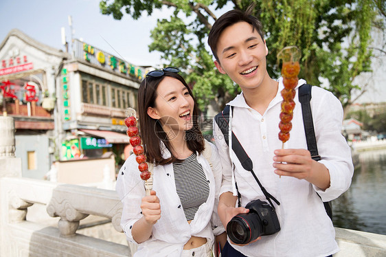 幸福欢乐青年情侣旅游拿着糖葫芦图片