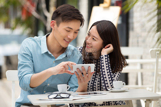 青年情侣坐在咖啡馆看手机图片