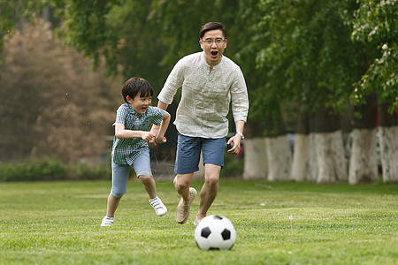快乐父子在草地上踢足球背景