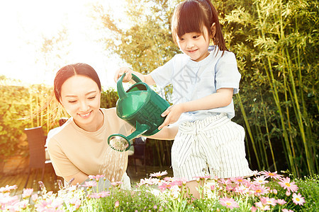 年轻的母亲和女儿在浇花图片