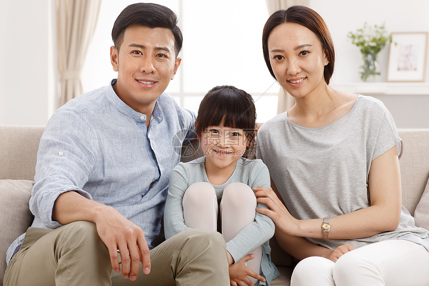 休闲装全家福爱幸福的一家三口坐在客厅里