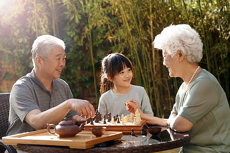 老年文化活动棋盘游戏象棋妻子老年夫妇和孙女在院子里下棋背景