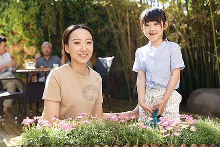 给植物浇水女孩夏天幸福家庭在庭院里背景