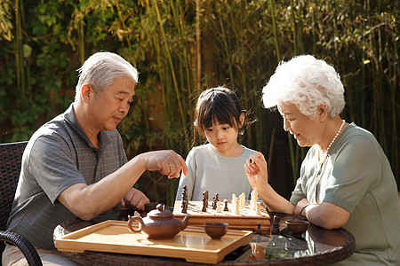 老年文化活动联系三个人老年夫妇和孙女在院子里下棋背景