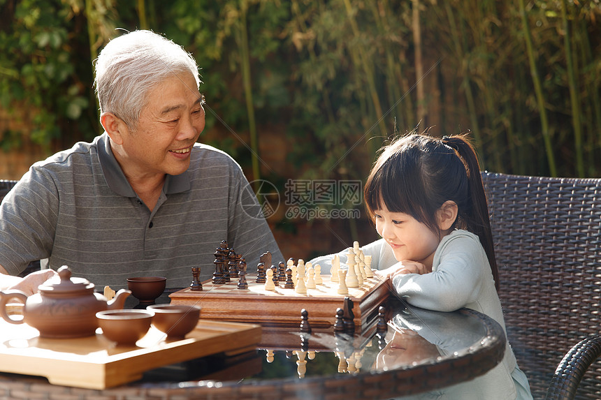 欢乐老年人象棋祖父和孙女在庭院里下棋图片