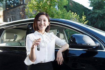 青年女人拿着车钥匙站在汽车旁边图片