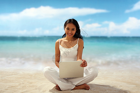 在海边使用笔记本电脑的女性图片