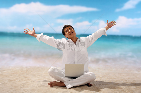 在海边使用笔记本电脑的男性图片