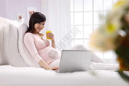 孕妇摄影维生素休闲装摄影孕妇坐在床上看电脑背景