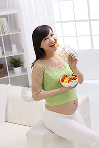 女性腹部孕妇在家吃水果背景