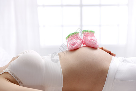 床水平构图侧面视角婴儿袜子放在孕妇的肚子上高清图片