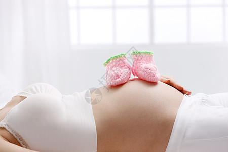 轻松纺织品青年女人婴儿袜子放在孕妇的肚子上图片