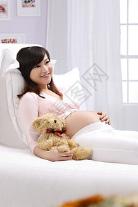 轻松东亚微笑孕妇躺在床上图片