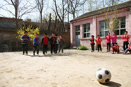 快乐儿童乡村小学生在学校里踢足球背景