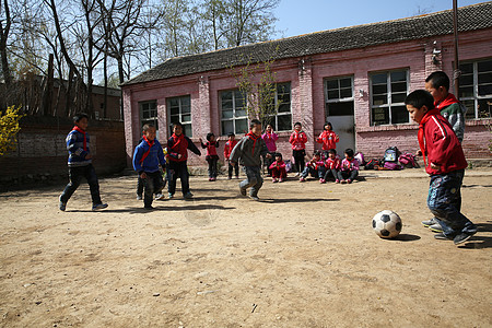 在跑步的孩子乡村小学生在学校里踢足球背景