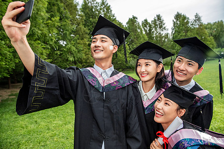 四个身穿学士服的大学生一起自拍高清图片