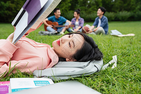 大学生躺在草地上享受课余时间图片