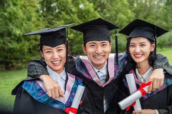 户外三个穿着学士服的大学生搂在一起图片