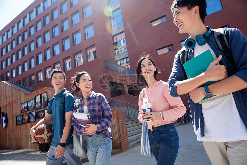 阳光下青年大学生情侣在校园里边走边聊图片