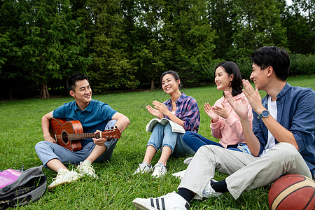 积极快乐的大学生在草地上弹吉他唱歌高清图片