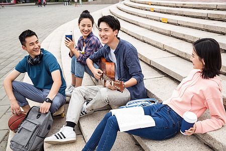 年轻的大学生坐在台阶上弹吉他高清图片