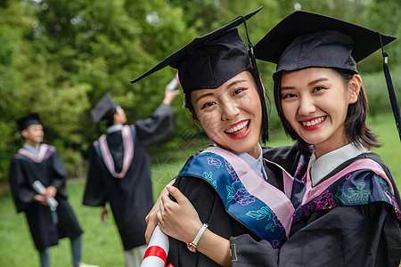 户外穿着学士服的大学生拥抱庆祝图片