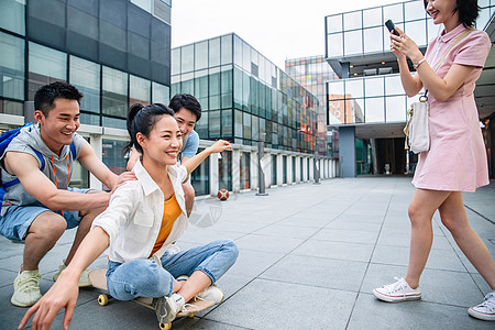 年轻男子向前推着坐在滑板上的女同学图片