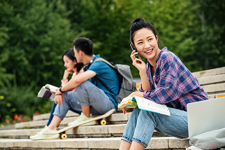 快乐的大学生坐在台阶上打电话高清图片