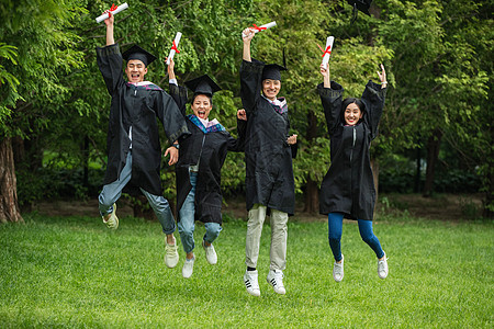 草地大学生穿着学士服庆祝毕业图片