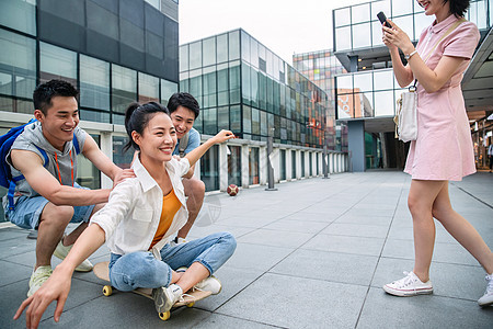 年轻男子向前推着坐在滑板上的女同学图片