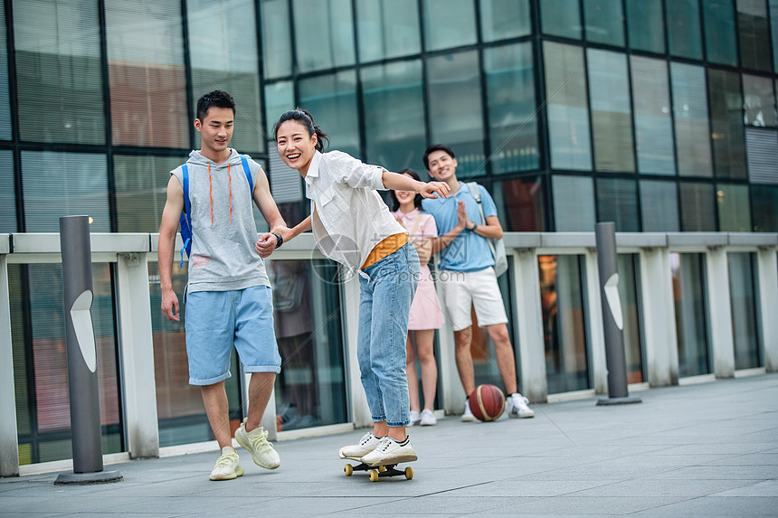 休闲装帅气的大学生教女朋友滑滑板图片