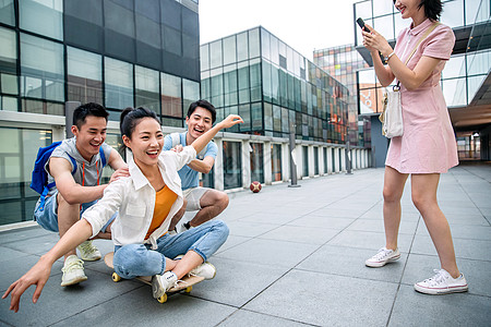 年轻男子向前推着坐在滑板上的女同学图片