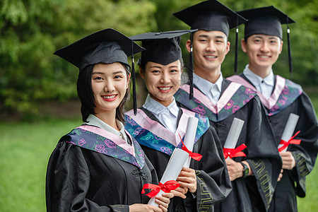 成功女性毕业生户外穿着学士服的大学生们背景