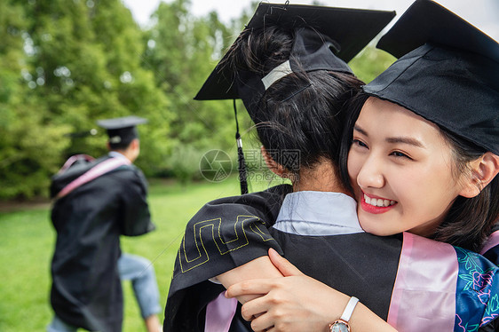 户外穿着学士服的大学生拥抱庆祝图片