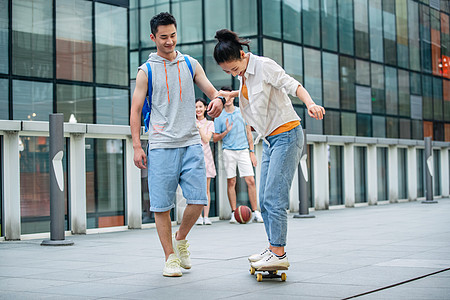 户外害怕的交流帅气的大学生教女朋友滑滑板图片