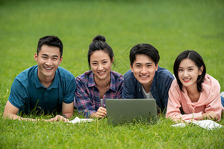 水平构图笔记本电脑幸福快乐的大学生趴在草地上学习图片