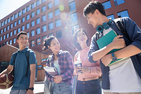 青少年户外阳光下四个大学生在校园里边走边聊背景
