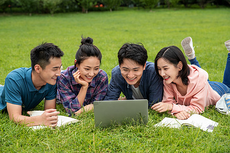 挨着不看镜头正面视角快乐的大学生趴在草地上学习图片