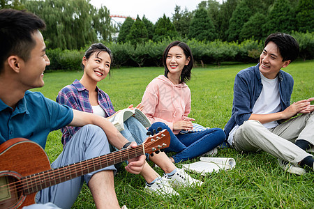 关爱青年人休闲装快乐的大学生在草地上弹吉他唱歌图片