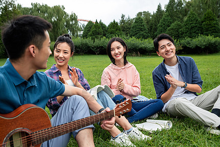 四个人弹奏课外活动快乐的大学生在草地上弹吉他唱歌图片