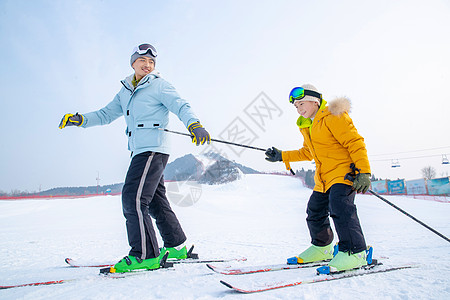 孩子嬉戏手套滑雪杖青年男人滑雪场上滑雪的快乐父子背景