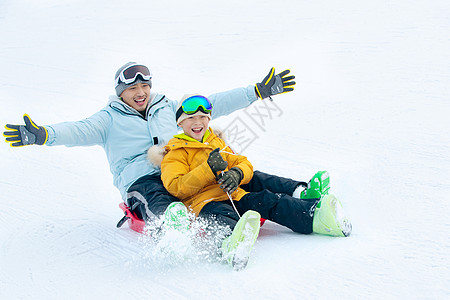 滑滑板男孩兴奋无忧无虑厚衣服快乐父子坐着雪上滑板滑雪背景