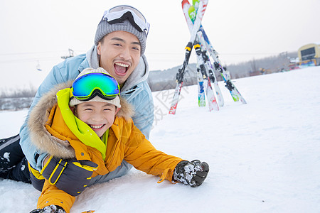 滑雪场内抱在一起打滚的快乐父子图片