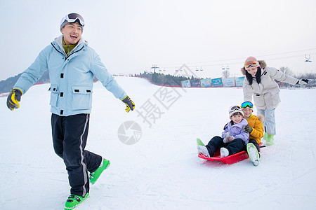 滑滑板男孩带儿子女儿冬日滑雪的父母背景