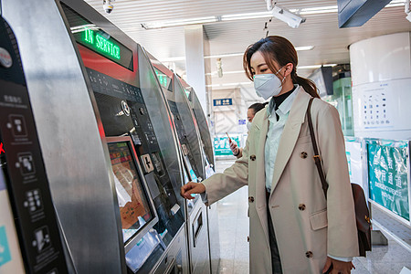 地铁站售票机戴口罩的年轻女人在地铁站使用自动售票机背景